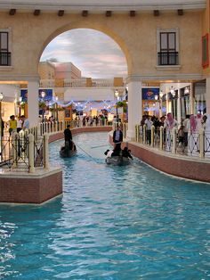 people are in the middle of an indoor swimming pool at a shopping mall while others watch