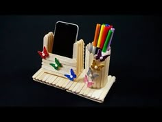 a cell phone holder made out of popsicle sticks and pencils on a black background