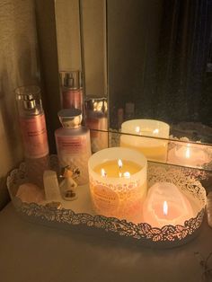 candles are lit on a tray in front of a mirror