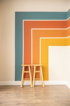 two wooden stools in front of a multicolored wall