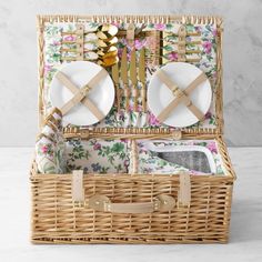 a wicker picnic basket with plates and utensils