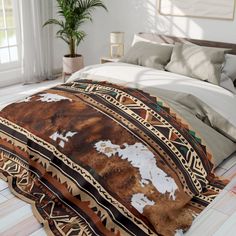 a bed with a brown and white blanket on top of it next to a potted plant