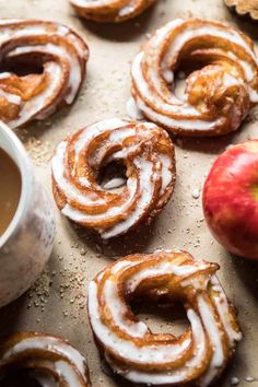 apple cider donuts with cinnamon glaze and an apple next to them on a baking sheet