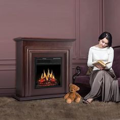 a woman sitting in front of a fire place reading a book next to a teddy bear