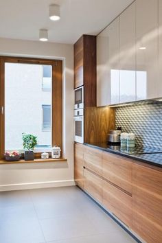 a kitchen with white tile flooring and wooden cabinetry next to a large window