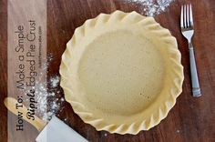 an uncooked pie crust next to a knife and fork on a wooden table