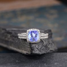 a tanzante and diamond ring sitting on top of a rock