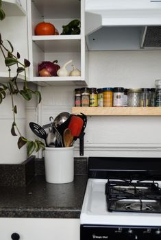 a stove top oven sitting inside of a kitchen next to a white cupboard filled with pots and pans