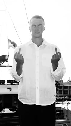 a man standing in front of a boat giving the peace sign