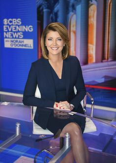 a woman sitting at a desk in front of a news anchor with her legs crossed