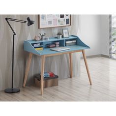 a blue desk with a lamp and pictures on the wall behind it in front of a window