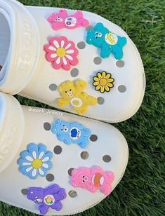 a pair of crocs with flowers and bears painted on them sitting in the grass