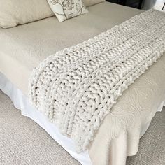 a white blanket on top of a bed next to pillows