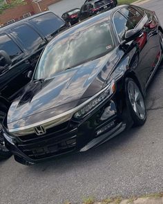 a black car parked next to other cars in a parking lot on the side of a road