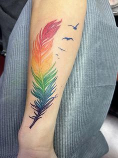 a colorful feather tattoo on the arm