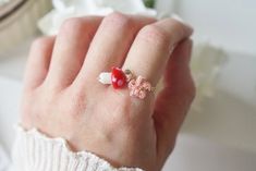 a woman's hand with a red and white flower ring on top of it