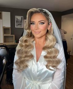 a woman with long blonde hair wearing a wedding dress and veil, posing for the camera