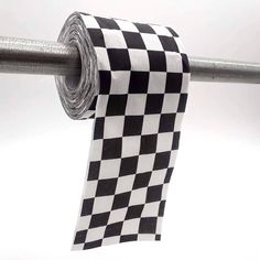 a roll of black and white checkered ribbon hanging from a metal bar on a pole