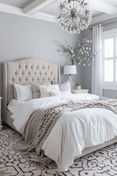 a bedroom with a bed, chandelier and pillows on the floor in front of a window