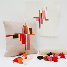 two pillows with tassels on the floor next to each other and a wall hanging