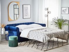 a bed sitting on top of a wooden floor next to a blue couch