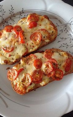 two slices of pizza on a plate with cheese and tomato toppings, ready to be eaten