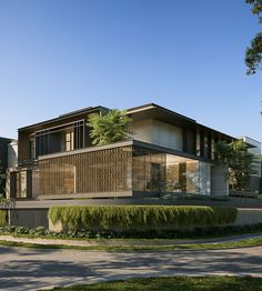 a large modern house on the corner of a street with grass and trees around it