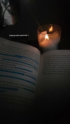 an open book sitting next to a lit candle