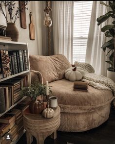 a living room filled with furniture and bookshelves next to a window covered in white curtains