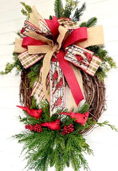 a christmas wreath hanging on the side of a white wall with red and green ribbon