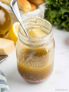 a jar filled with liquid next to bread and vegetables