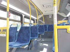 the inside of a bus with blue seats and yellow railings on both sides,