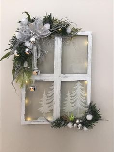 an old window decorated with christmas decorations and greenery is hung on the wall in front of it