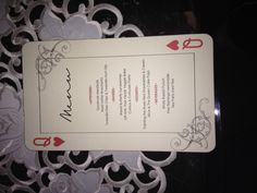 a menu card sitting on top of a lace covered table cloth with red and white designs