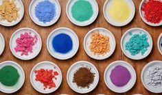 several bowls filled with different colored powders on top of a wooden table