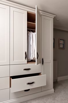 an empty closet with white cabinets and drawers