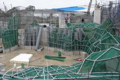 the construction site is covered with green tarps and scaffoldings, while workers are on the roof