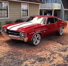 a red and white car parked in front of a house