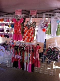 there are many different types of clothing on display at this market stall, including dresses and t - shirts