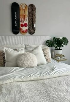 a white bed topped with lots of pillows next to two surfboards on the wall