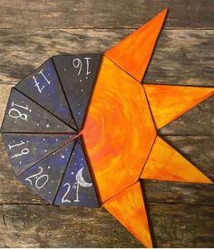 an orange and blue clock sitting on top of a wooden table next to a piece of wood