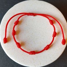 two red string bracelets sitting on top of a white plate