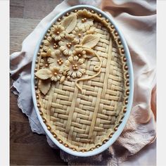 an image of a pie with flowers in the center on a wooden tableclothed surface