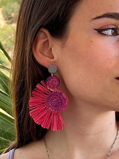 a close up of a person wearing some kind of earring with pink and purple colors