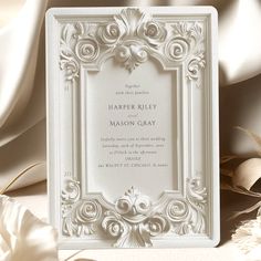 a white wedding card with an ornate frame