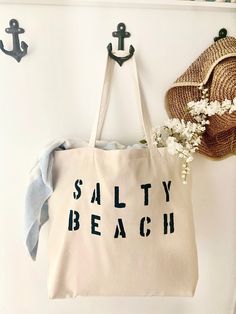 "The SALTY BEACH over sized canvas tote bag is perfect minimalist bag for a trip to the beach! Available with text in several colors... check out the variations! This bag is made from 100% thick, sturdy canvas. AVAILABLE IN TWO SIZES * Large - 19.5\" x 13\" with a 4\" gusset *Jumbo - 23\" x 13\" with a 6\" gusset These bags are hand painted using non-toxic fabric paint. The technique used creates an attractive distressed appearance to the text that varies from bag to bag. All of my products are Trendy Canvas Bag For Beach Season, Summer Large Capacity Cotton Beach Bag, Large Capacity Cotton Beach Bag For Summer, Cotton Canvas Bag For Daily Use And Beach Season, Beige Cotton Bags For Beach Season, Large Capacity Cotton Bag For Beach Season, Beige Cotton Bag For Beach Season, Cotton Beach Tote Bag For Beach Season, Cotton Tote Beach Bag For Beach Season