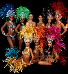 a group of women in colorful costumes posing for a photo with some feathers on their heads