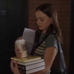 a woman holding books and a cup in her hand