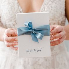 a person holding a card with a blue bow on it