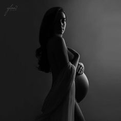 a pregnant woman is posing for a black and white photo with her hands on her hips